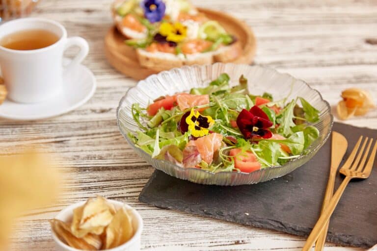 Fresh Mediterranean pescetarian salad with salmon, vegetables, greens and edible flowers.